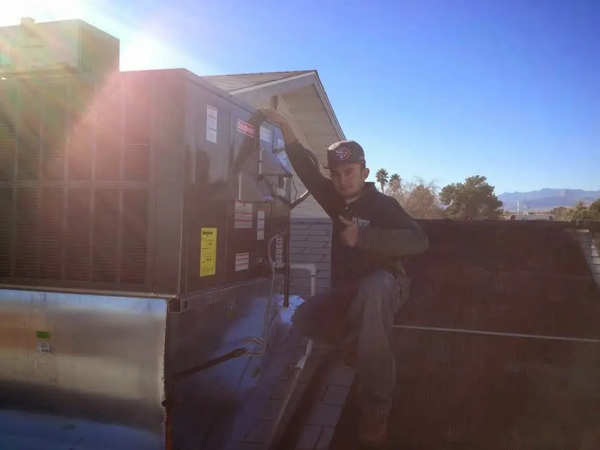 HVAC technician performing AC Tune-Up on a rooftop unit in Ledyard